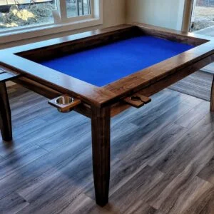 A table with a sunken middle surface for playing board games. sits in a living room with windows behind it, The table has cupholders and trays around the perimeter for holding drinks and game pieces