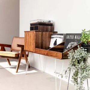 Angled shot of a solid walnut record cabinet with a cherry tambour door, set in a bright modern living space.