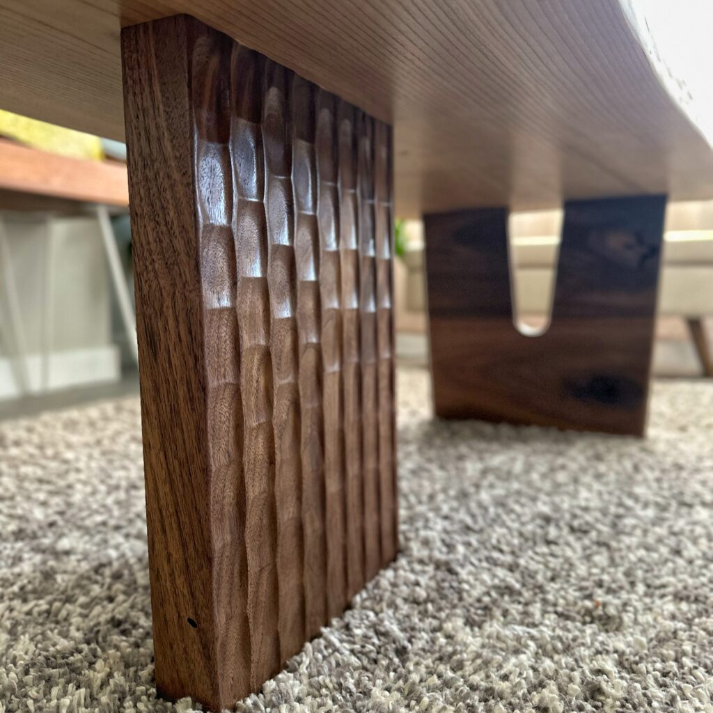 Close-up view of a coffee table leg featuring a textured pattern, showcasing the craftsmanship and detail in the woodwork.